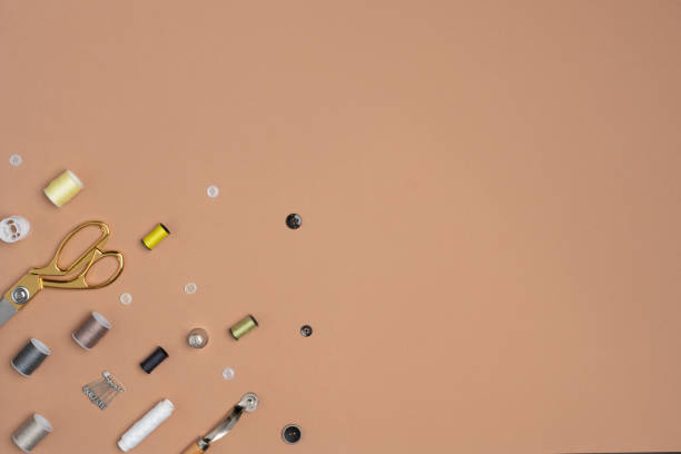 istock Sewing accesories such as spools of thread, scissors, and buttons aesthetically arranged on the beige background. 1412440271