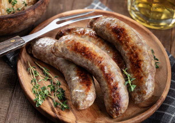 Fried bratwurst garnishrd with thyme Fried bratwurst garnished with thyme on a plate on a rustic wooden table bratwurst stock pictures, royalty-free photos & images