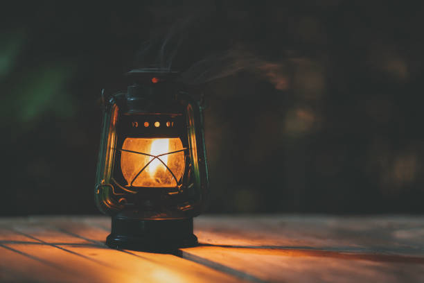 夜の木製の床にライトが付いているアンティークの灯油ランプ - oil lantern ストックフォトと画像