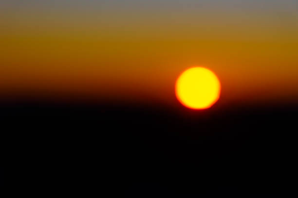 Sunrise in Australia; a dramatic contrast of red and black behind the gold disc of the sun stock photo