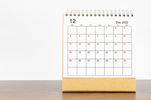 December 2022 desk calendar with plant on wooden table.