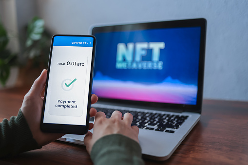 Trader doing NFT payment on metaverse market using cryptocurrency exchange app - Focus on mobile phone