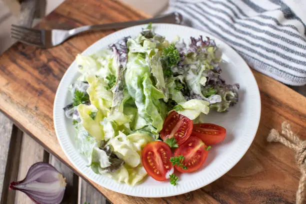 Delicious homemade marinated side salad with tasty sour cream dressing. Served on wooden cutting board