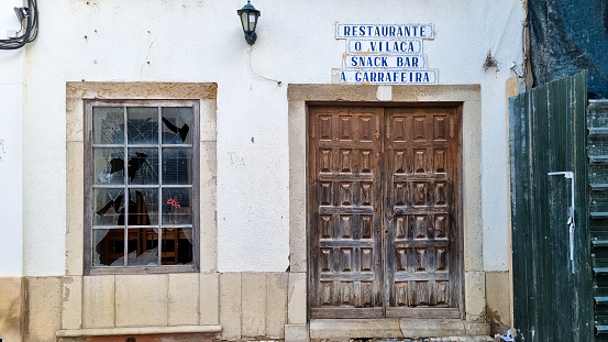 Faro, Portugal - April, 2022: Abandoned cafe building, broken window, in the city center; 