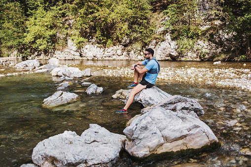 Young adult sporty man fitness and triathlon training in nature. He is running through fresh mountain river. People and extreme sports concept.