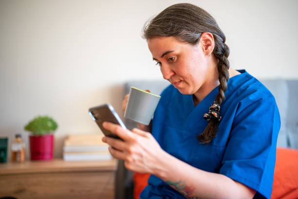 istock Woman with Scrubs using smart phone at home 1412450335