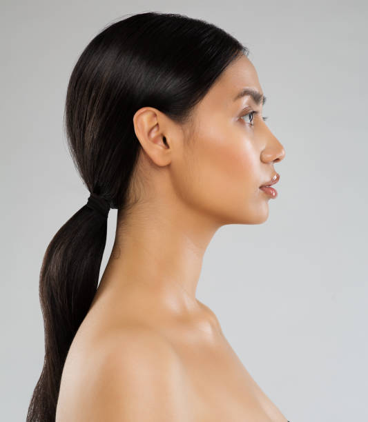 perfil de la modelo de belleza. mujer joven con pelo largo de cola de caballo. vista lateral de la cara de las mujeres sobre el fondo gris. dama con maquillaje natural y peinado de cola negra - ponytail side view women human head fotografías e imágenes de stock