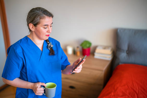 istock Woman with medical scrubs using smart phone 1412451136
