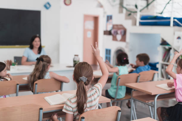 istock A teacher reads a book to elementary school students who listen carefully while sitting in a modern classroom 1412453436