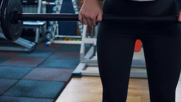 istock Athletic woman pumps muscles using a barbell with a weight. Classes in the gym using extreme bar weights. Reducing excess weight in the gym due to physical activity. Physical exercise. 1412454465
