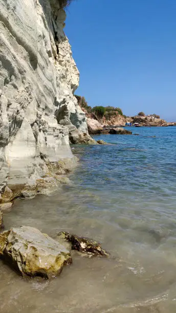 View of the rocky beach on the coast of the island of the Mediterranean Sea on the shores of the blue sky