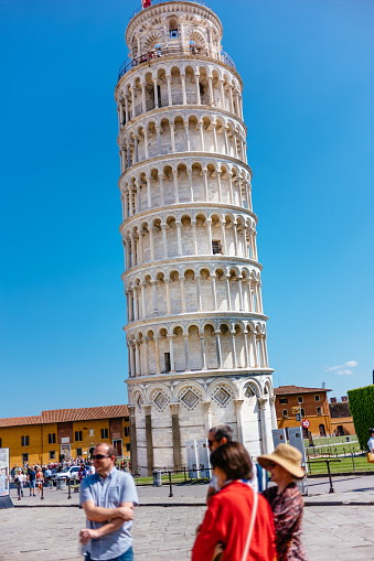 Leaning Tower of Pisa, with tourists in the foreground, on a clear sunny day in Tuscany, Italy.