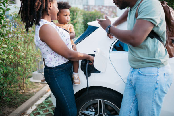 Family standing next to their electric vehicle stock photo