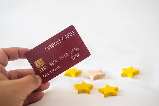 Holding a red credit card and four star shape. The concept of pay by credit card and people review comments and rating or feedback for evaluation.