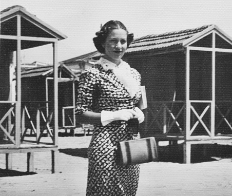 Young beautiful woman in front of beach huts in tourist resort. 1939.