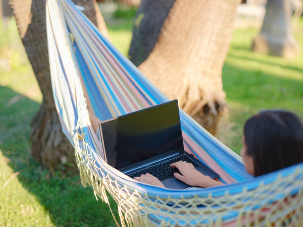 istock Young business woman working at computer in a hammock 1412465701