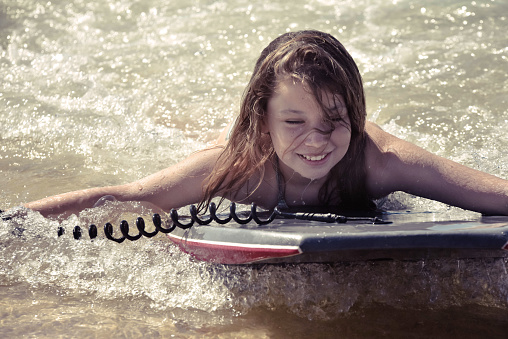 Pretty young girl sliding on the waves of the atlantic ocean