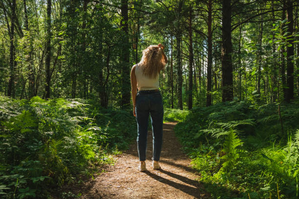 istock The young woman walks through a dark forest on a sunny day 1412468506