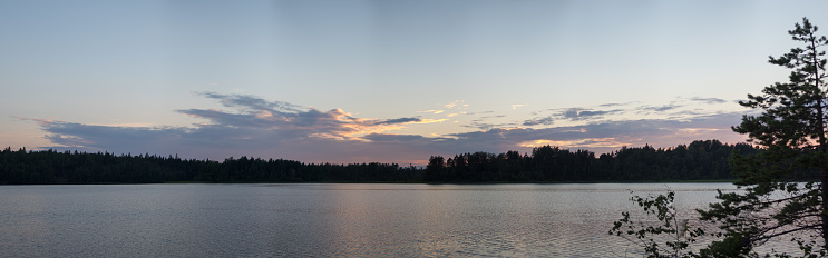 sunset panorama with clouds over forest lake
