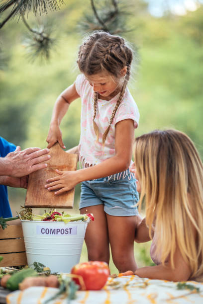 family composting kitchen waste outdoors stock photo