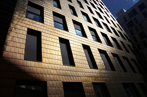 An ethereal abstract image shot at the golden hour of the metal facade architecture of a modern building.  There are lines and angles moving through this high-contrast image. The image features a close up of an office building in Miamisburg Ohio