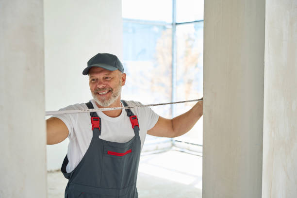 joyful gray-haired builder measures width of doorway with tape measure - men baseball cap focus determination imagens e fotografias de stock