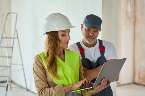 istock Manager holds open laptop and shows it to builder 1412474602