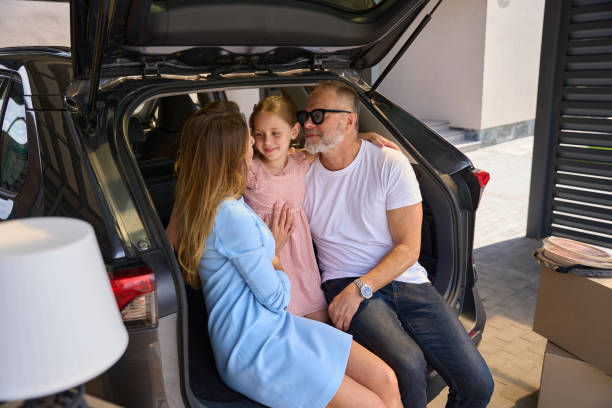 istock Father, mother and daughter gently hugging sit in car 1412476667
