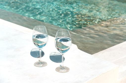 This is a photograph of two glasses of drinking water set next to an outdoor pool with no people in Tulum, Mexico.