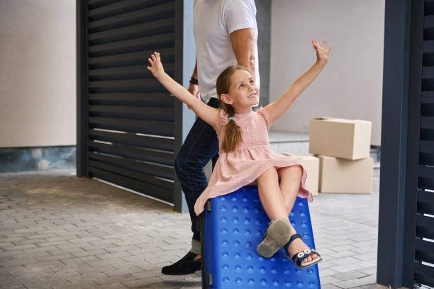 istock Daughter sits on a suitcase held by her father 1412477940