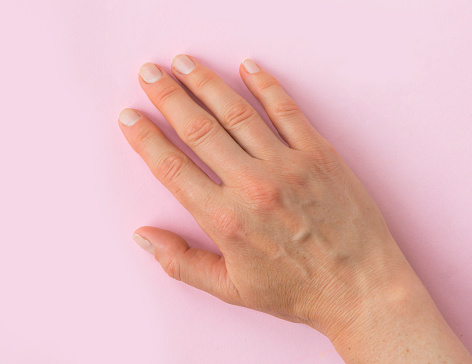 Right female adult hand on a pink background