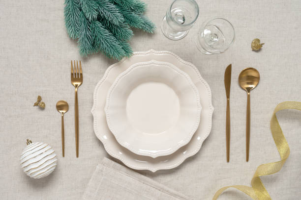 istock Christmas table setting on a beige linen tablecloth. Top view, flat lay. Beige plates, golden cutlery and Christmas decorations. 1412479352