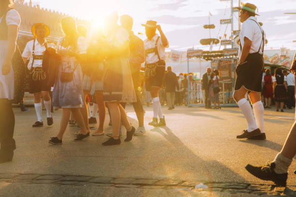 München, Deutschland - 29. September 2016: Besucher spazieren durch das Oktoberfest in München, Deutschland. Die Frau trägt typisches Dirndl und die Herrenlederhose - die traditionelle bayerische Kleidung. Das Oktoberfest ist das größte Bierfest der Welt mit über 6 Millionen Besuchern pro Jahr.