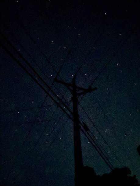 A silhouette of a telephone pole pictured amongst a background of stars.￼￼