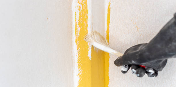 istock Home renovation concept, hand paint brush, applying to plaster surface. White and yellow. 1412481129