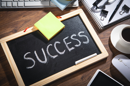 Success text on blackboard with a coffee and other objects.