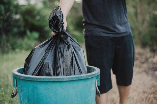 istock A man holding a large garbage bag, is dropping it into a trash. 1412482039