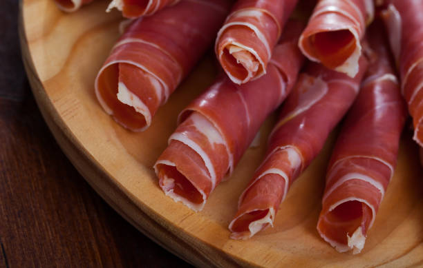 Spanish tasty meal rolls of prosciutto di parma at wooden desk Spanish tasty meal rolls of prosciutto di parma at wooden desk, close up prosciutto stock pictures, royalty-free photos & images