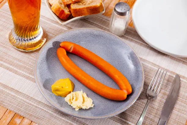 Photo of Thin frankfurters served with white horseradish, mustard and beer