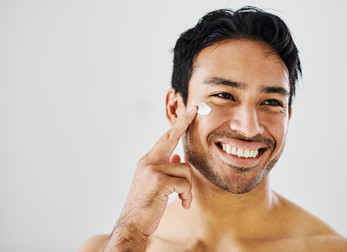 Skincare, healthy skin and selfcare routine using moisturizer to achieve a clean and flawless complexion. Handsome and happy male using cream to hydrate and protect while practicing good hygiene
