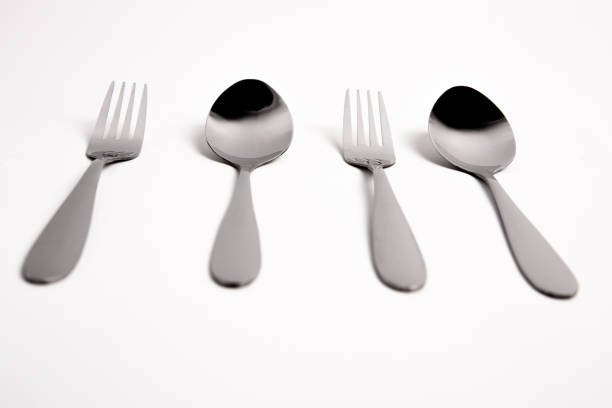 hicken egg on metal forks, spoons isolated on white background close-up. An egg that is set on top of two forks, spoons. Eggs have so many uses from diet to baking recipes.