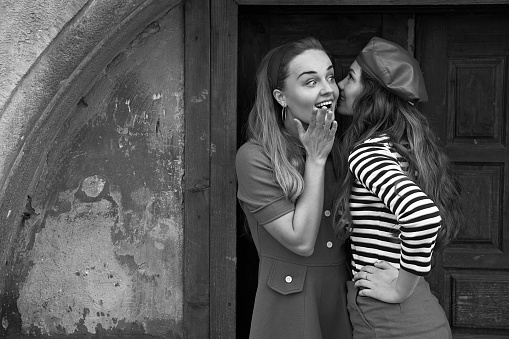 Young beautiful girls dressed in retro vintage style enjoying the old european city summertime lifestyle. Chatting in the street. Black and white.
