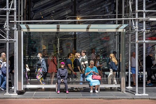 New York, NY, USA - June 23, 2022: People waiting for the bus in a shed under a scaffolding on 5th Avenue in midtown Manhattan
