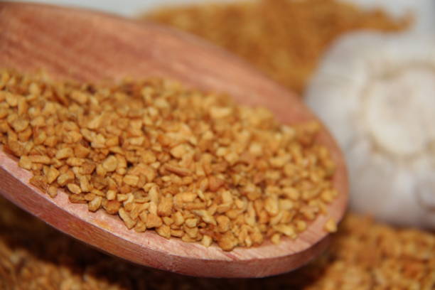 istock Fried minced garlic with wooden measuring spoon with garlic bulb. 1412490681