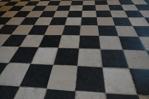 Photograph on a black and white checkerboard floor.\nThere is a perspective effect