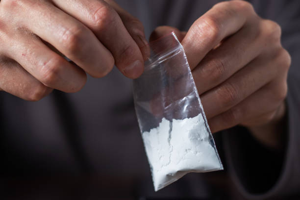 Concept drug addiction. Man hand holds plastic packet or bag with cocaine or another drugs Concept drug addiction. Man hand holds plastic packet or bag with cocaine or another drugs, drug abuse and danger addiction concept. wrongful death stock pictures, royalty-free photos & images