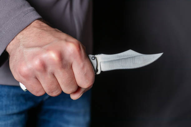 istock Man holding a knife in a threatening stance ready to fight 1412496175