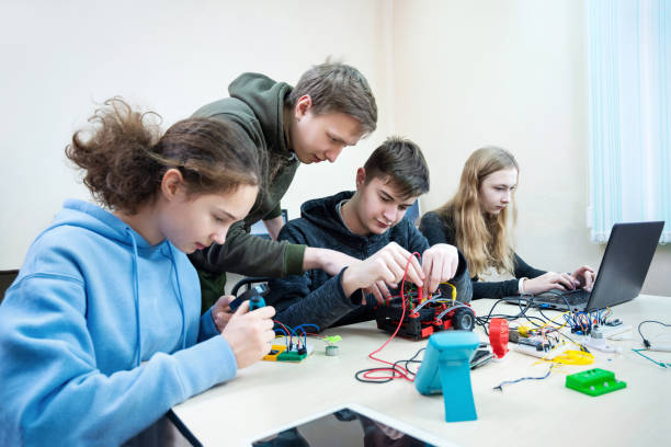 istock Diverse teenager pupils build robot vehicle learning at table at STEM engineering science education class. 1412500549