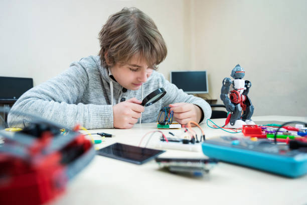 istock Teenager boy at robotics school makes robot managed from the constructor, child learns robot constructing. 1412500827