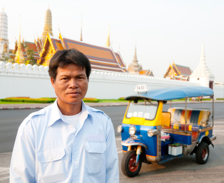 Tuk-tuk driver waiting for a customer in front of Bangkok's most famous landmark, the Grand Palace.